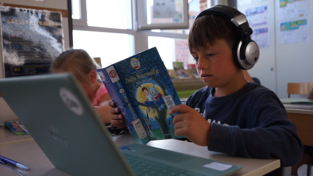 Een kind met dyslexie leest een gedrukt boek en luistert tegelijk naar het luisterboek